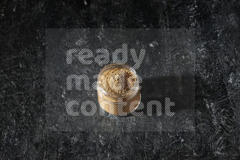 وعاء زجاجي ممتلئ ببودرة بهار الفلفل الحلو على خلفية سوداء