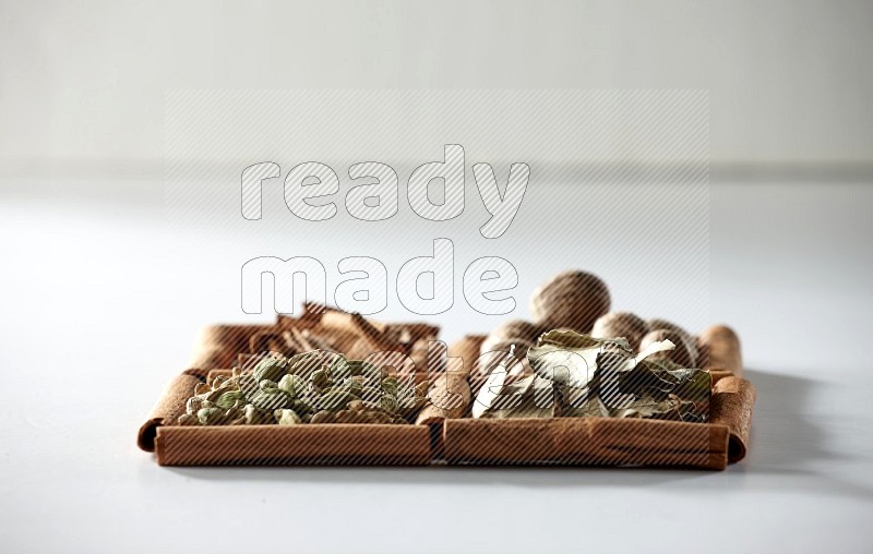 4 squares of cinnamon sticks full of nutmegs, bay laurel leaves, cardamom and cinnamon on white flooring