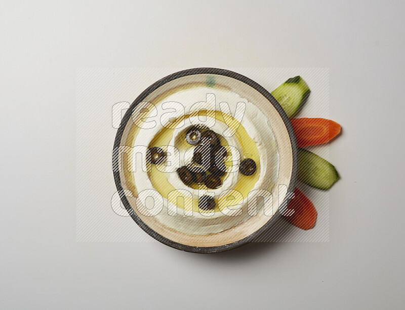Lebnah garnished with sliced olives in a pottery plate on a white background