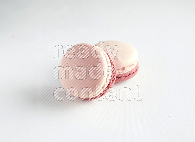 45º Shot of two Pink Litchi Raspberry macarons on white background