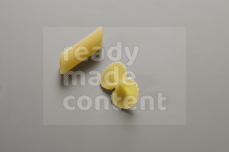 Penne pasta with other types of pasta on grey background