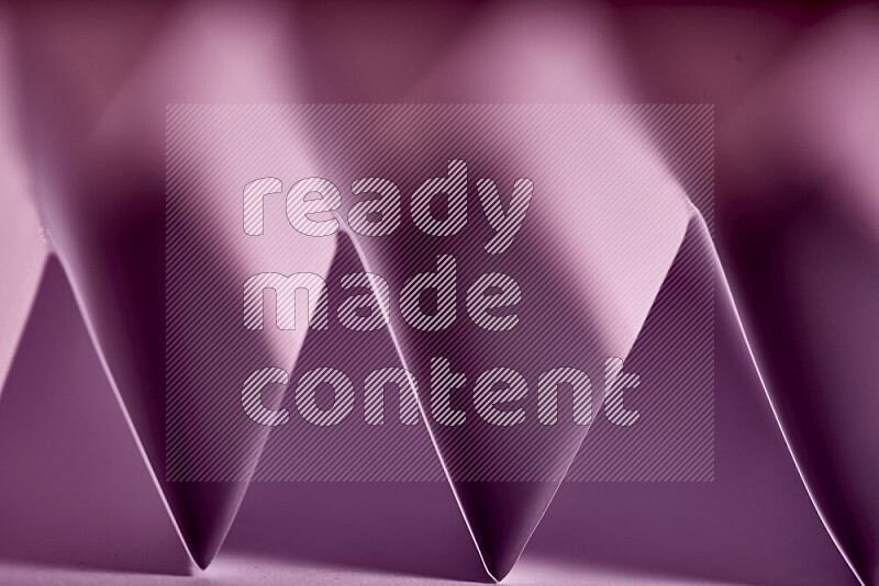 A close-up abstract image showing sharp geometric paper folds in purple gradients