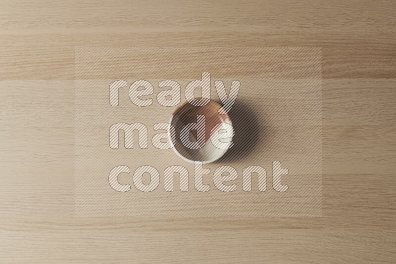 A multicolored pottery bowl on light wooden background