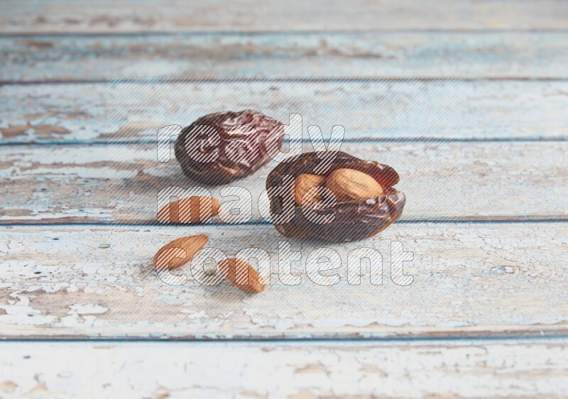 two almond stuffed madjoul dates on a light blue wooden background