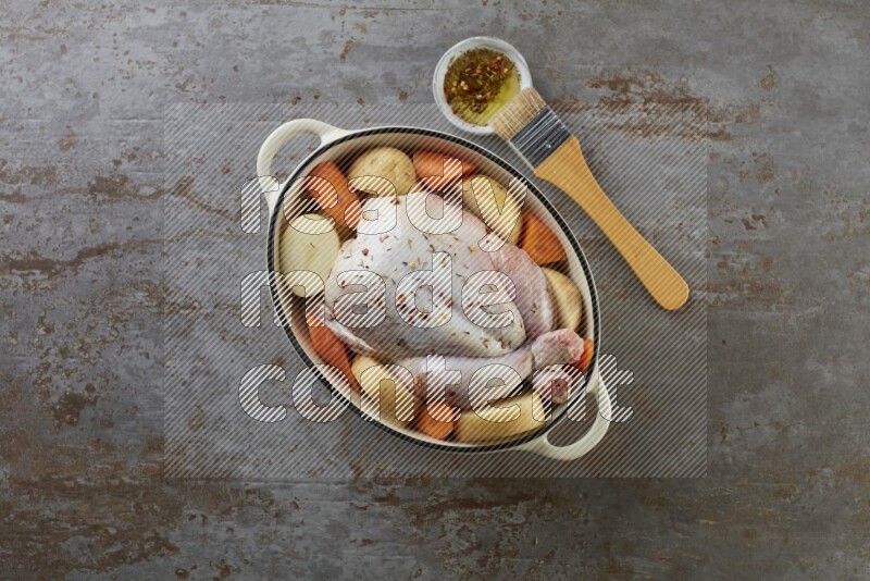 whole raw chicken on in a white ceramic pot direct on a rustic grey background