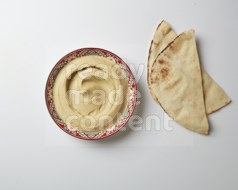 Plain Hummus in a red plate with patterns on a white background