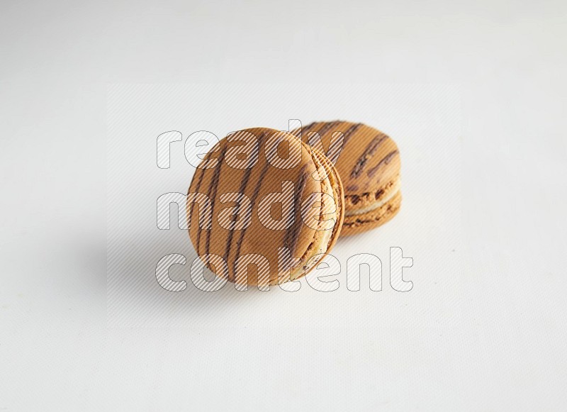 45º Shot of two light brown  Almond Cream macarons on white background