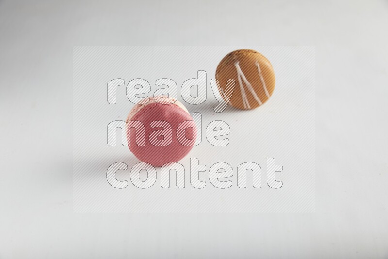 45º Shot of of two assorted Brown Irish Cream, and Pink Litchi Raspberry macarons on white background