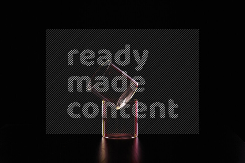 Glassware with rim light in red and yellow against black background