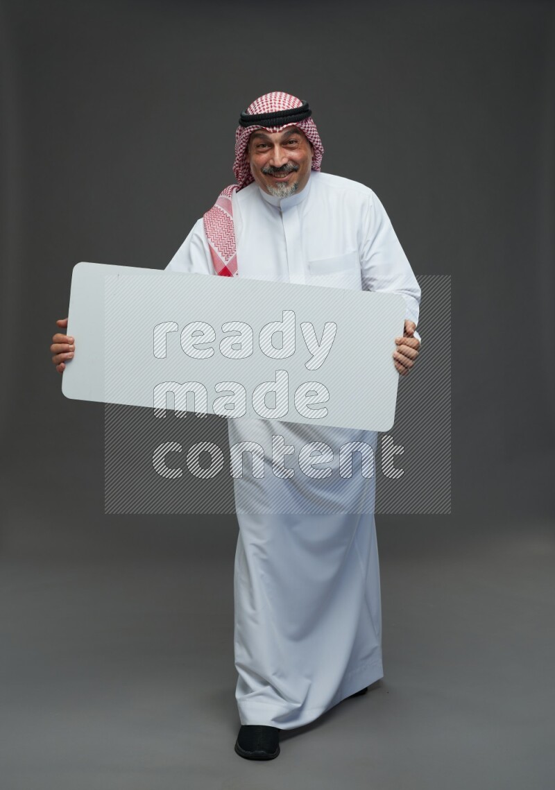 Saudi man with shomag Standing holding social media sing on gray background