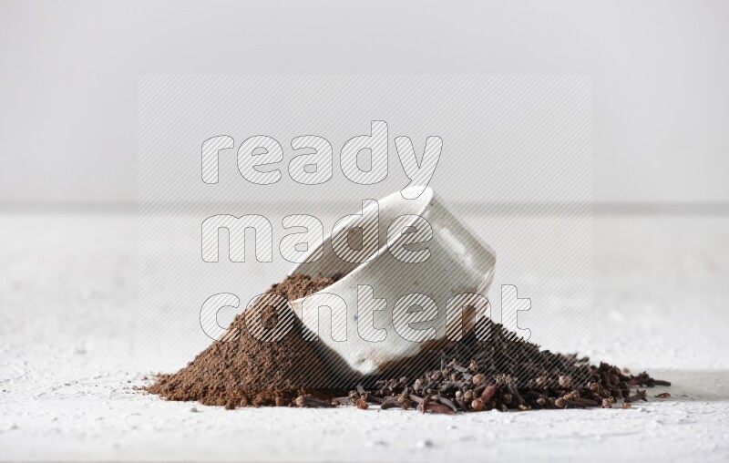 وعاء بيج من السيراميك ممتلئ ببودرة القرنفل وبعض بودرة القرنفل سقطت بخارجه على أرضية بيضاء