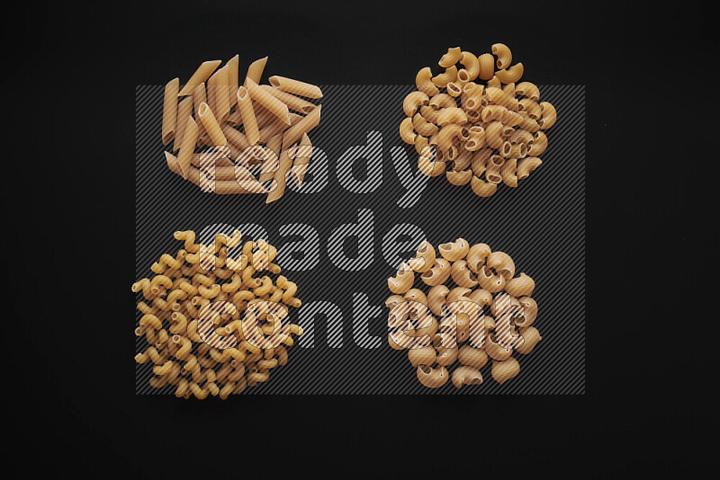 Different pasta types in bunches on black background