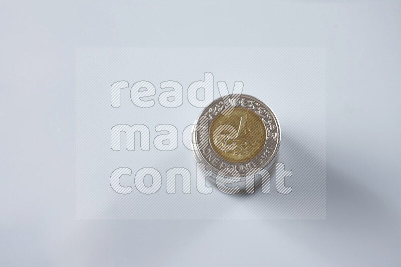 كومة من عملات النقود المصرية بقيمة جنيه واحد على خلفية رمادية