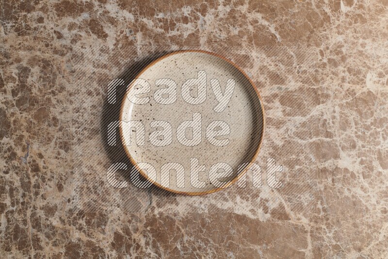 A beige pottery plate on beige marble background
