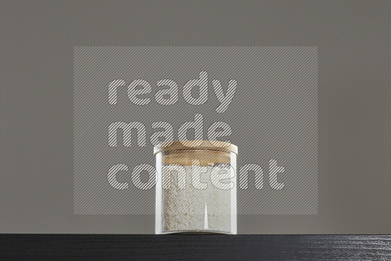 Desiccated coconut in a glass jar on black background
