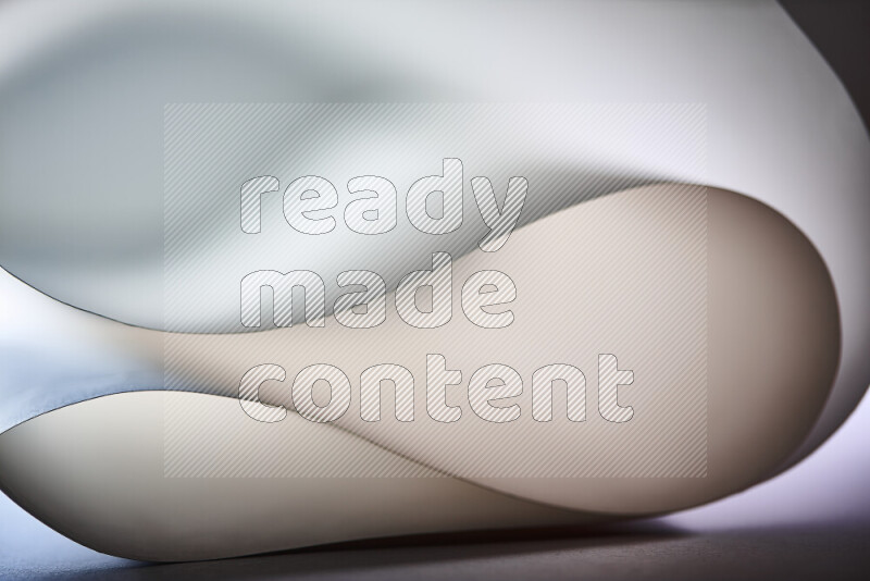 An abstract art piece displaying smooth curves in grey gradients created by colored light