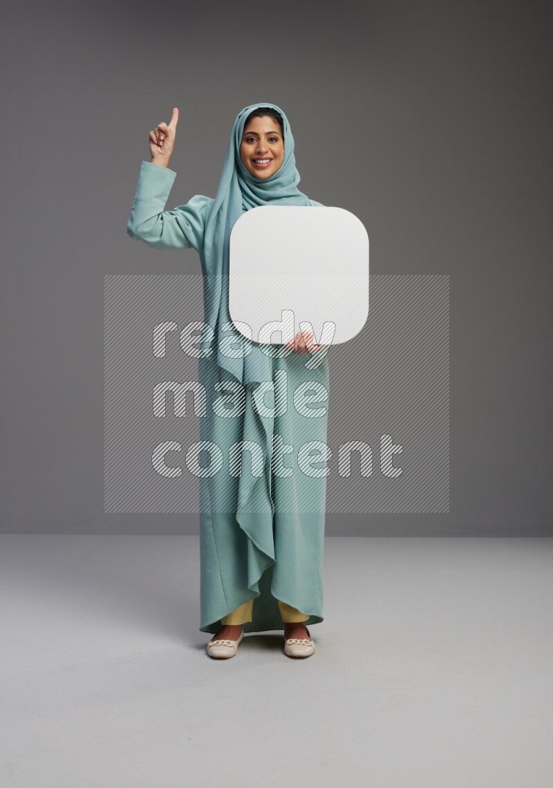 Saudi Woman wearing Abaya standing holding social media sign on Gray background
