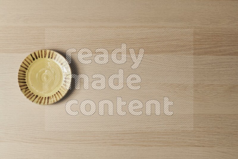 صحن فخاري متعدد الألوان على خلفية خشبية فاتحة