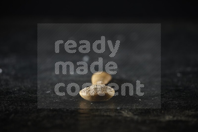 ملعقة خشبية ممتلئة ببودرة الهيل على خلفية سوداء