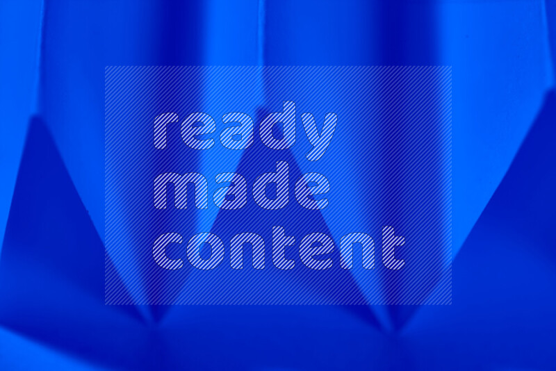 صورة مجردة مقربة تظهر طيات ورقية هندسية حادة بتدرجات اللون الأزرق