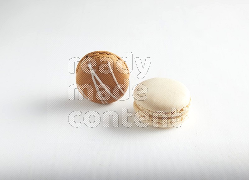 45º Shot of of two assorted Brown Irish Cream, and White Caramel fleur de sel macarons on white background