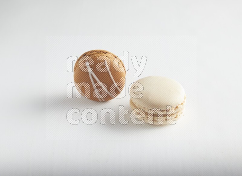 45º Shot of of two assorted Brown Irish Cream, and White Caramel fleur de sel macarons on white background