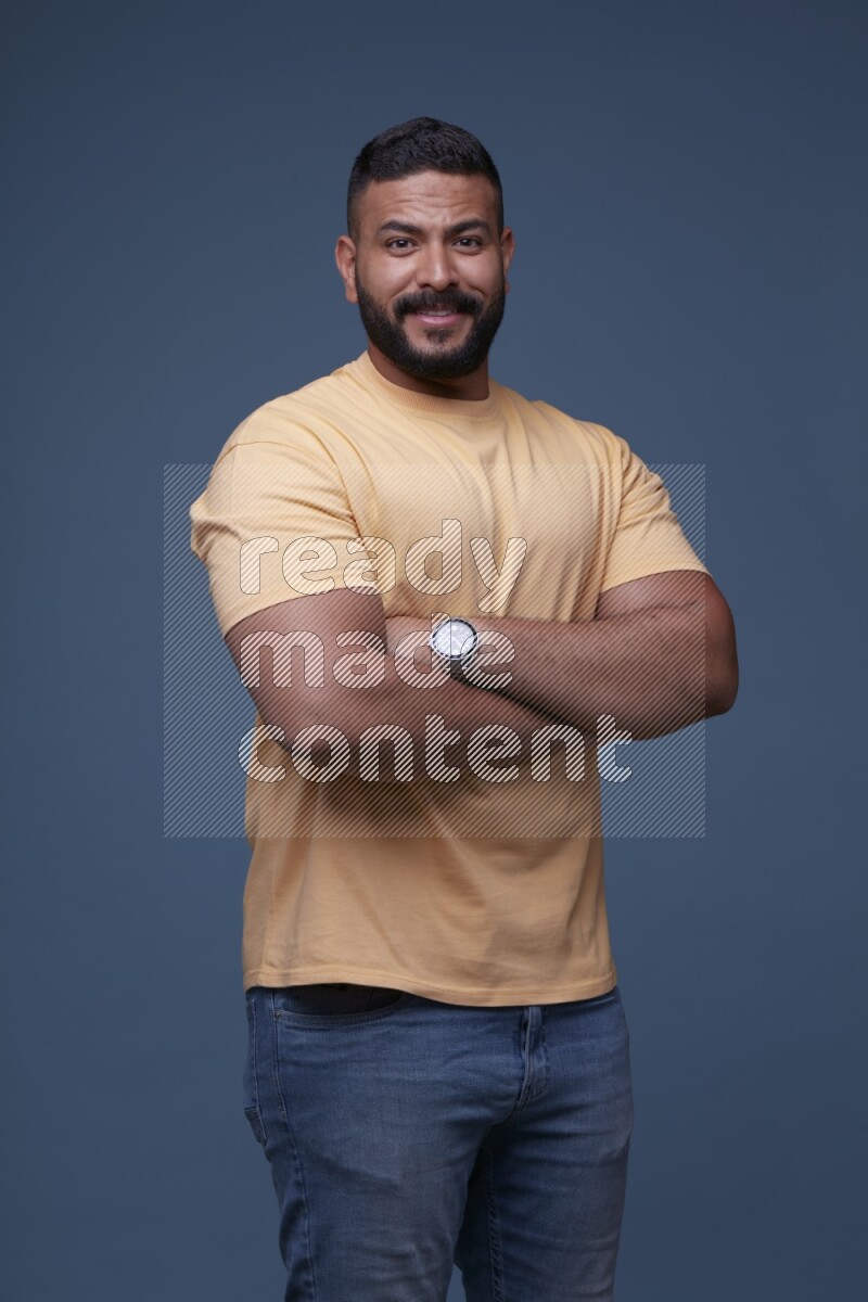 A man posing in a blue background wearing a yellow shirt