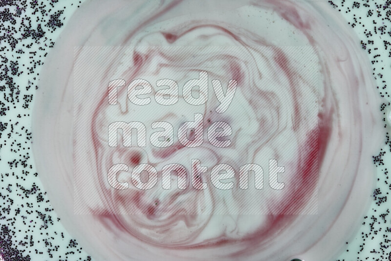 A close-up of swirls of red with sparkling purple glitter scattered on green background