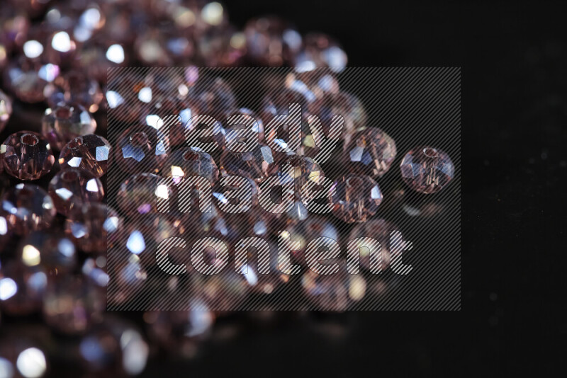 Rose transparent crystal beads scattered on a black background