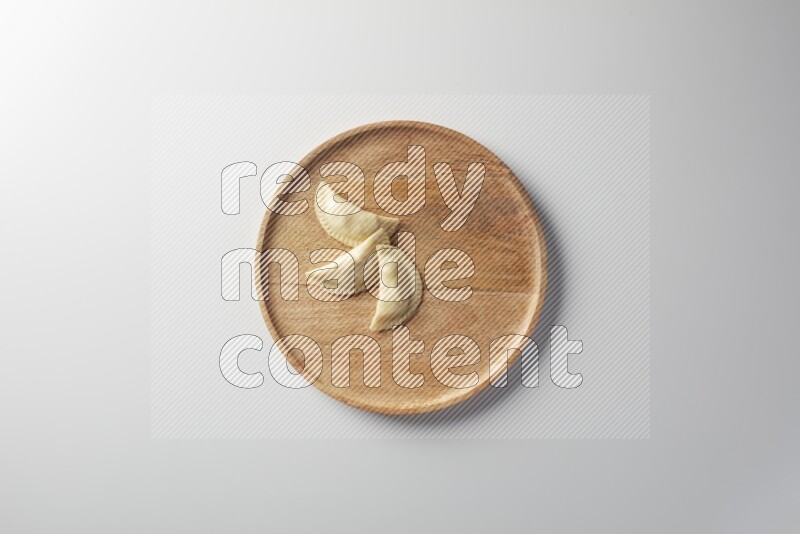 Three Sambosas on a wooden round plate on a white background