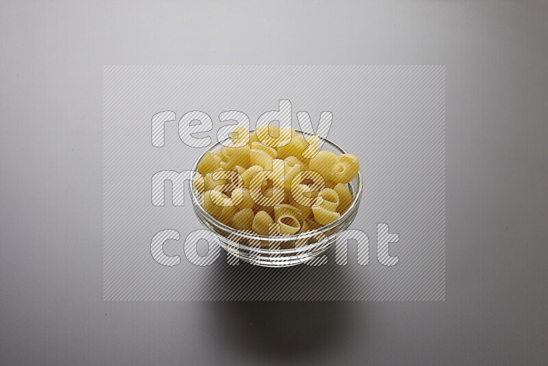 Pipe pasta in a glass bowl on grey background