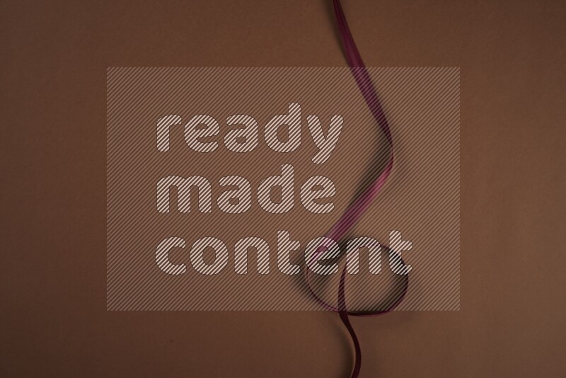 A red collection of sewing and tailoring tools arranged on a brown background