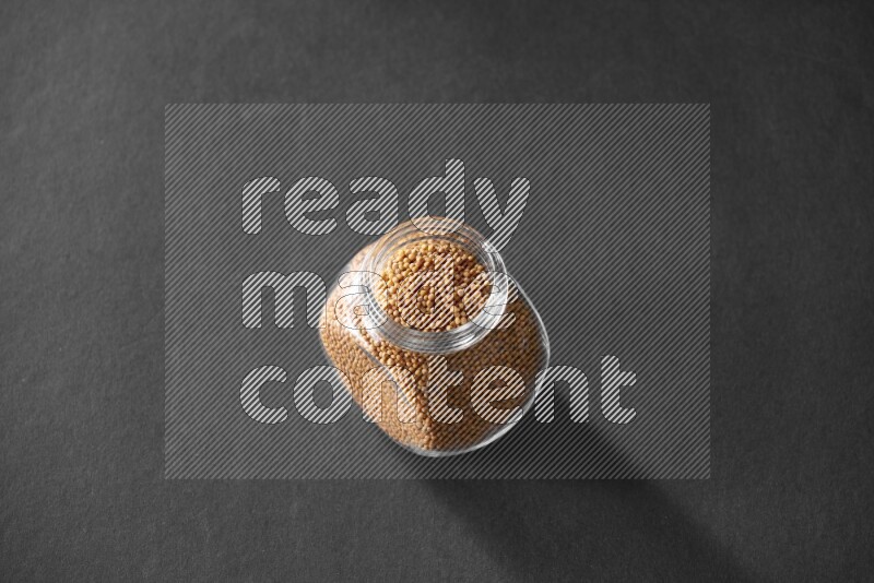 حبوب الخردل في وعاء زجاجي علي خلفية سوداء