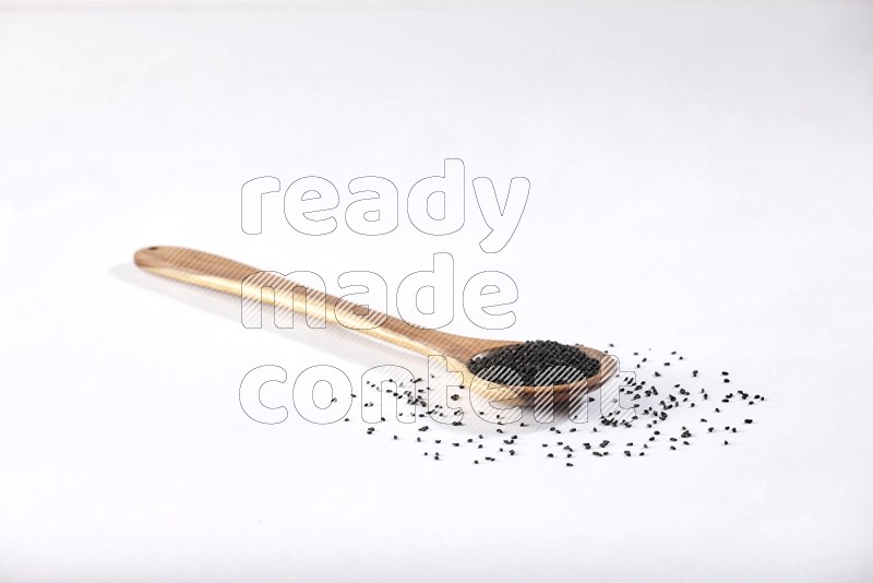 A wooden ladle full of black seeds on a white flooring in different angles