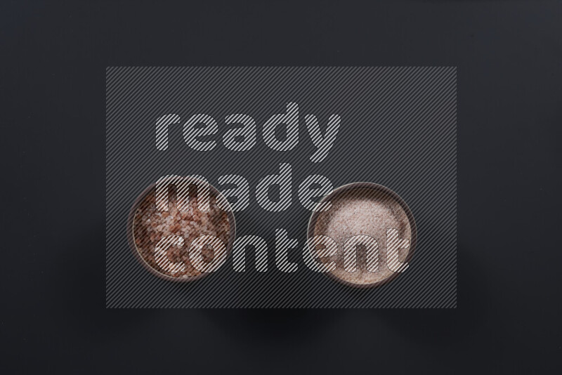 وعاء فخاري ممتلئ بملح الهيمالايا الناعم وملح الهيمالايا الخشن على خلفية سوداء