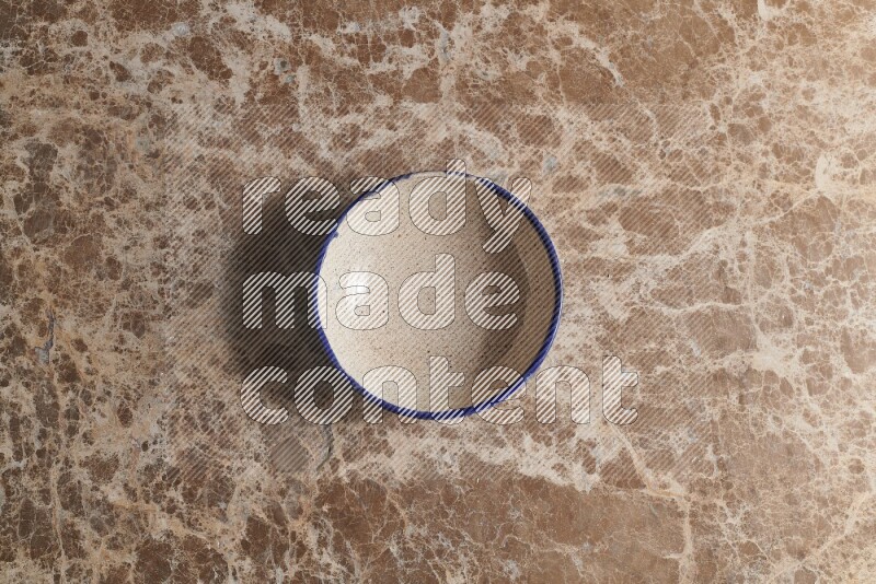 A multicolored pottery bowl on beige marble background