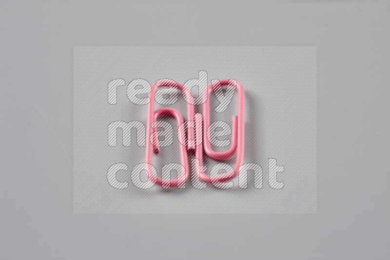 Pink paper clips isolated on a grey background
