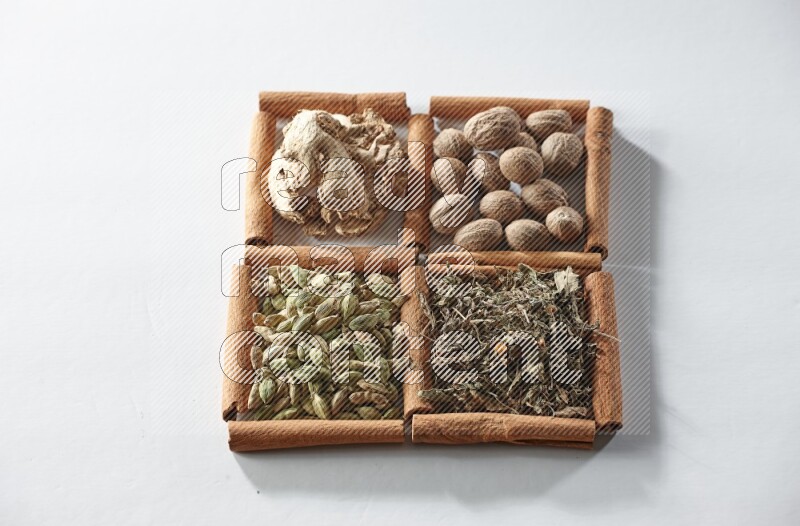 4 squares of cinnamon sticks full of nutmegs, dried ginger, cardamom and dried basil on white flooring