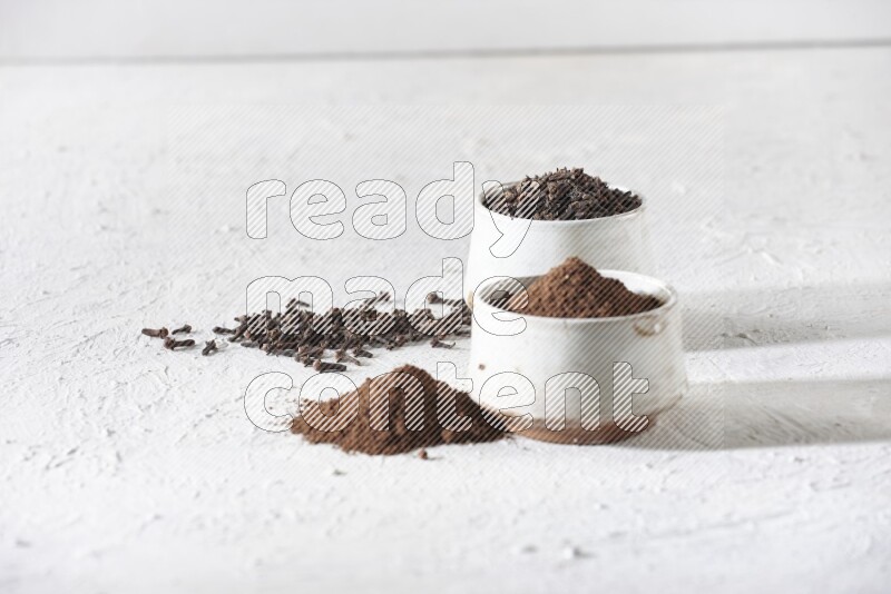 وعاءين من السيراميك بيج اللون، أحدهما مملوء بالقرنفل والآخر مملوء بالبودرة على أرضية بيضاء