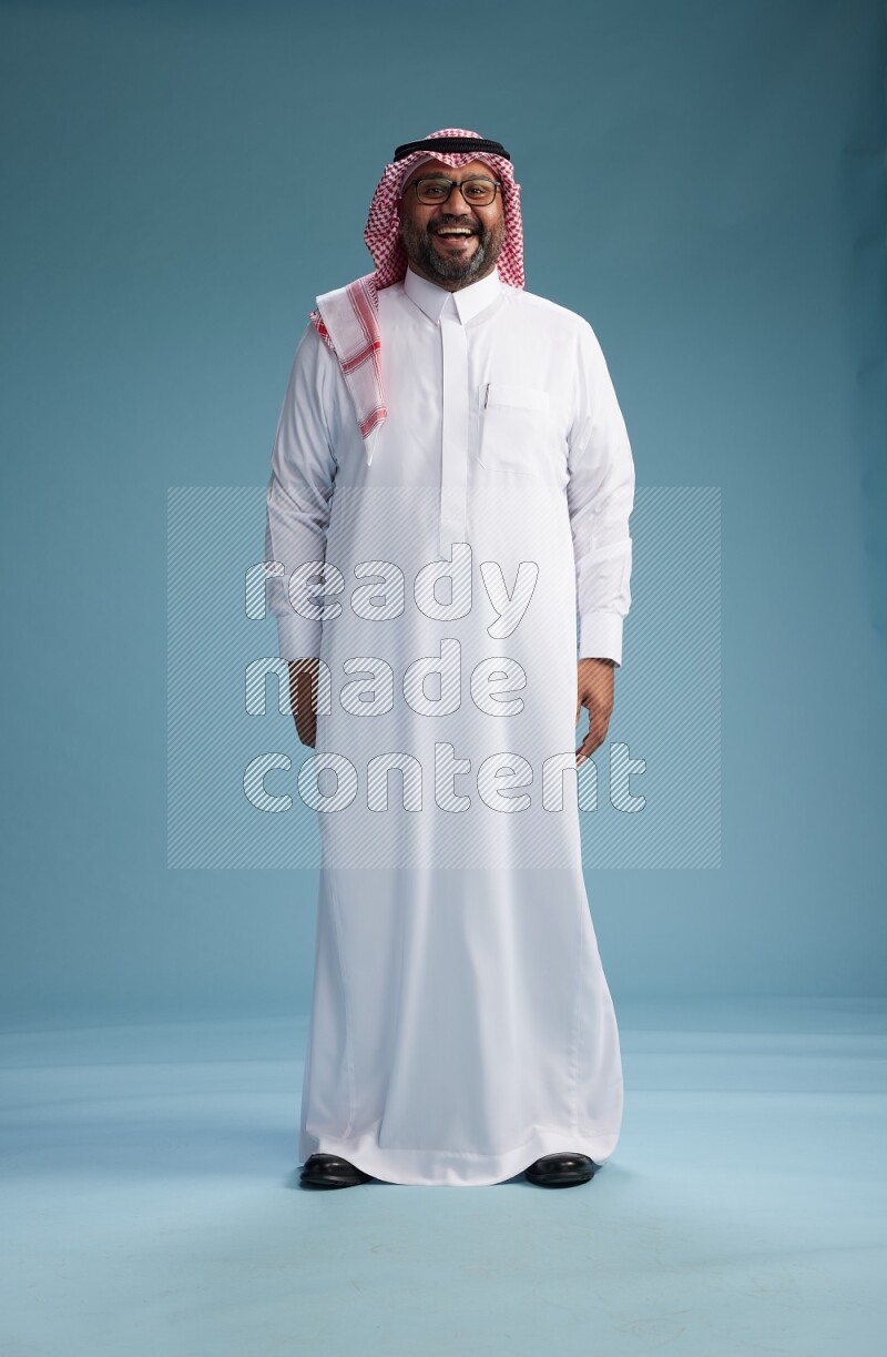 Saudi Man with shimag Standing Interacting with the camera on blue background