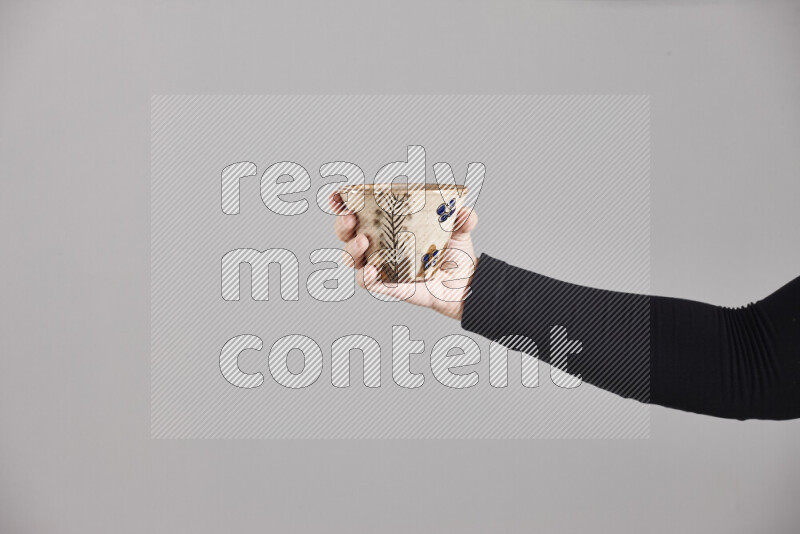 A woman in black abaya holding different pottery essentials in different positions