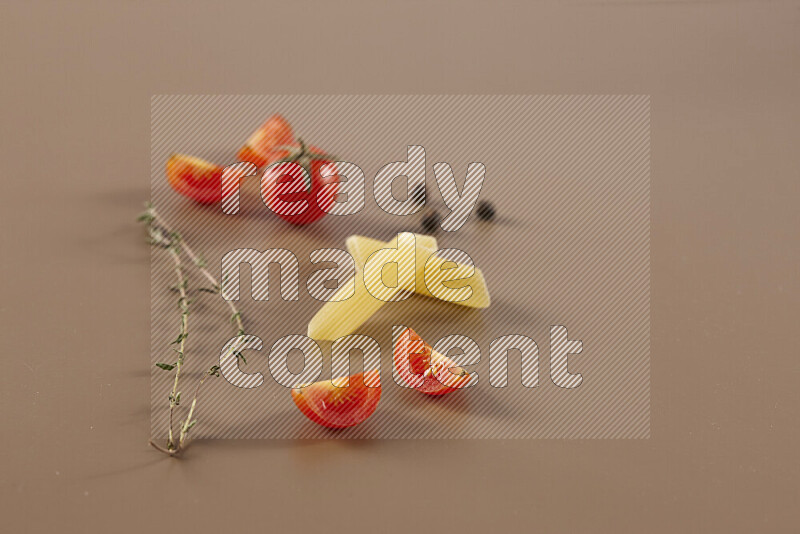 Raw pasta with different ingredients such as cherry tomatoes, garlic, onions, red chilis, black pepper, white pepper, bay laurel leaves, rosemary and cardamom on beige background