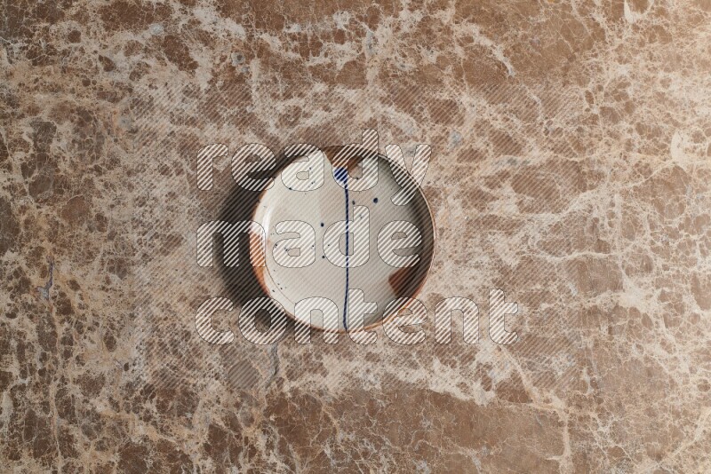 A multicolored pottery plate on beige marble background