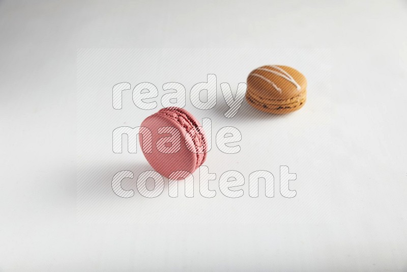 45º Shot of of two assorted Brown Irish Cream, and Pink Raspberry macarons on white background