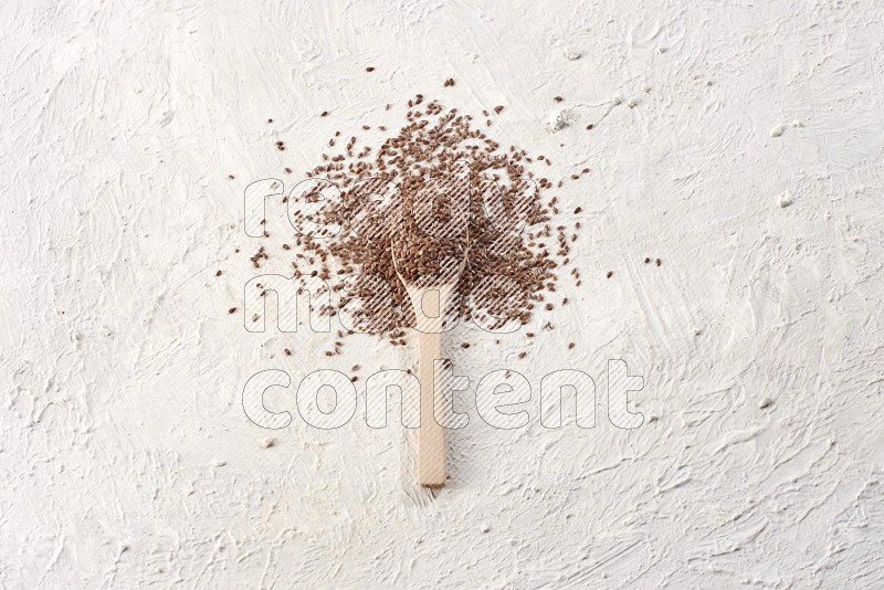 A wooden spoon full of flax surrounded by flax seeds on a textured white flooring in different angles