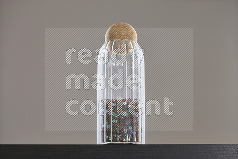 Sequins in a glass jar on black background