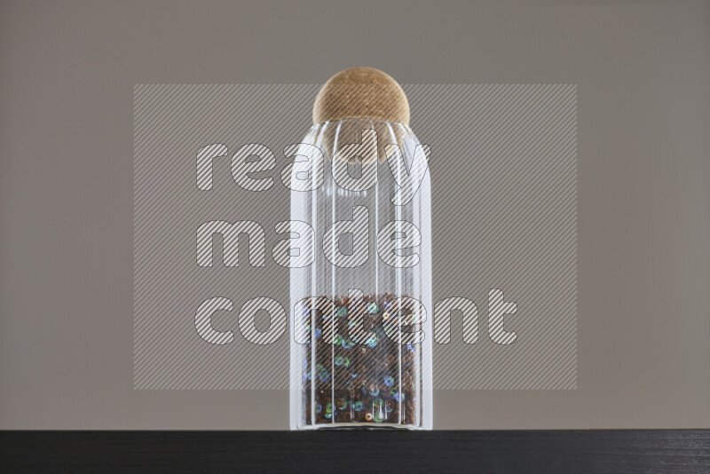 Sequins in a glass jar on black background