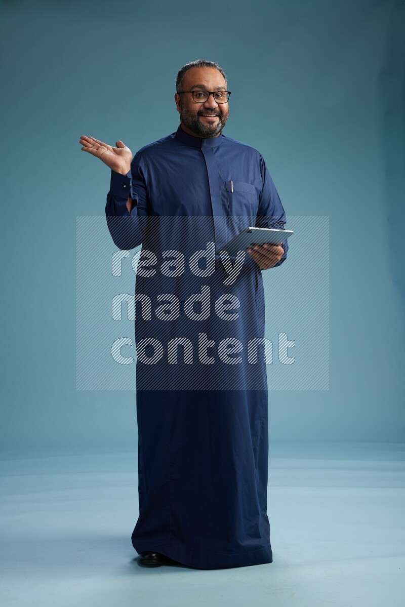 Saudi Man without shimag Standing working on tablet on blue background