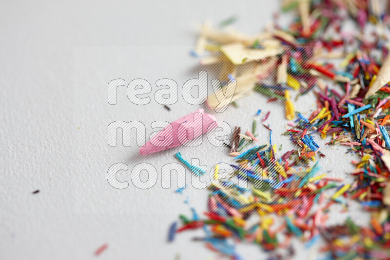 This image showcases a vibrant multicolored pencil shavings scattered on grey background