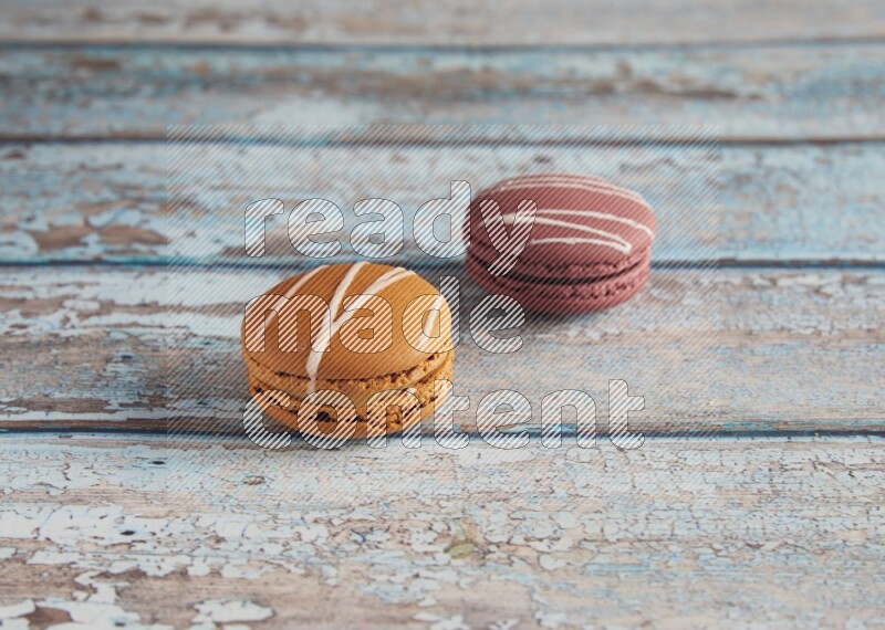 45º Shot of of two assorted Brown Irish Cream, and Red Poppy Flower macarons  on light blue background